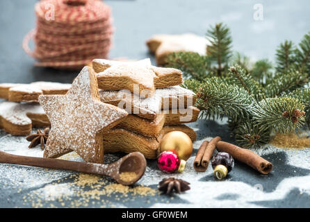 Cooked Christmas holiday traditional gingerbread cookies with sugar powder, anise and cinnamon sticks on black background Stock Photo
