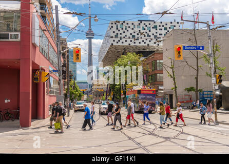 Dundas and Mccaul corner in Toronto with people walking in the crosswalk and CN tower in the background Stock Photo