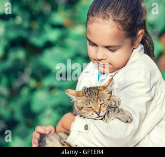 Cute sad girl hugging a cat in the garden Stock Photo