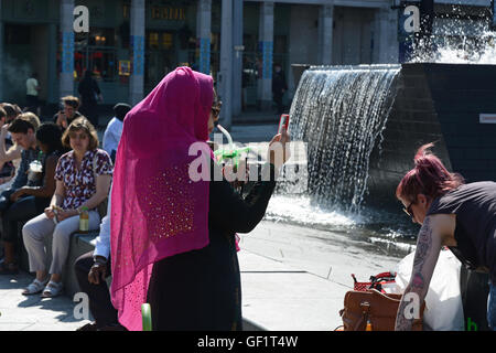 Muslim woman in Pink hijab, taking photograph on mobile phone. Stock Photo