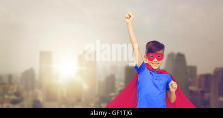 boy in red superhero cape and mask showing fists