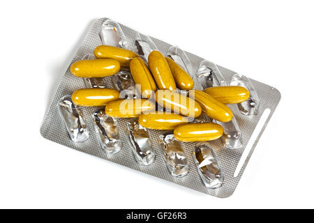 Studio above shot of mustard colored capsules on top of empty blister pill pack on white Stock Photo