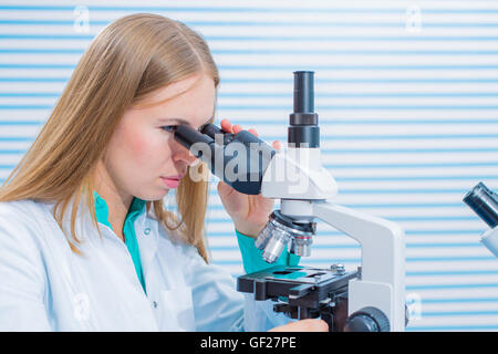 Female scientist looking through a microscope in laboratory Stock Photo
