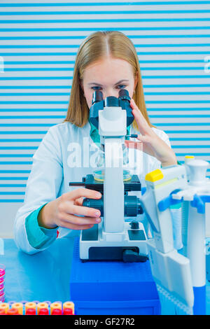 Female scientist looking through a microscope in laboratory Stock Photo