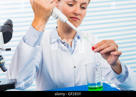 Young female researcher using pipette in medical laboratory Stock Photo