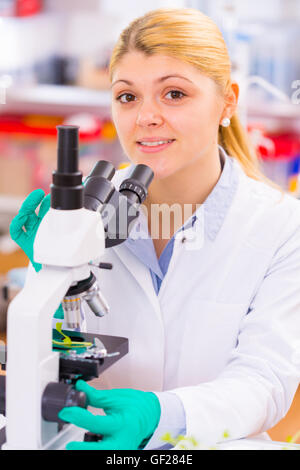 Female scientist looking through a microscope in laboratory Stock Photo