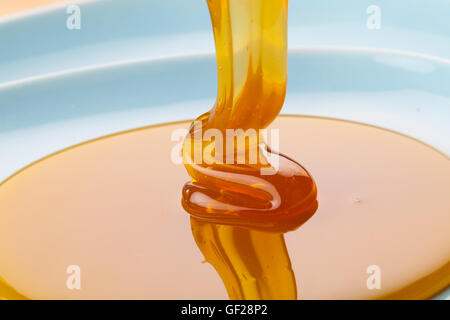 Honey flowing on blue background. Stock Photo