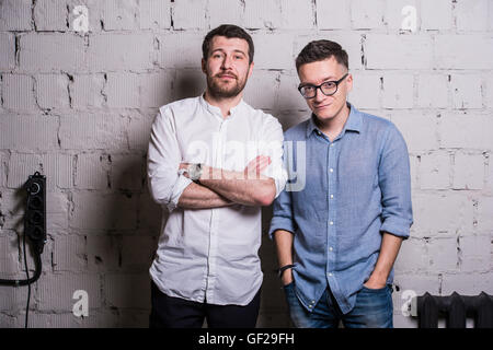 Two young men startupers over grey brick wall loft interior design Stock Photo