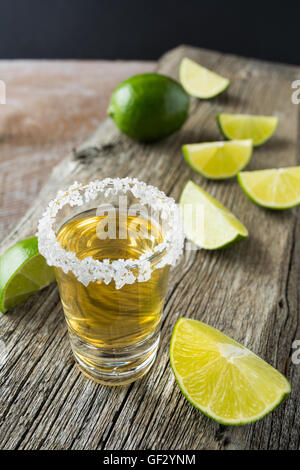 Gold tequila shot with lime slices on rustic wooden table. Gold Mexican tequila shots. Strong alcohol  drink. Stock Photo