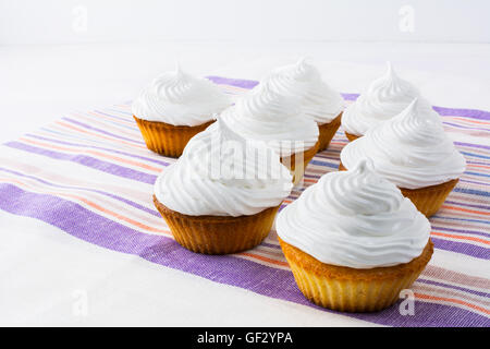 Row of white cupcakes on the striped  linen napkin. Homemade cupcakes with whipped cream.  Birthday cupcake. Stock Photo