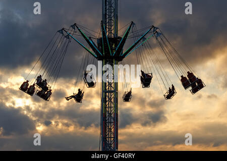 People enjoying swing ride at sunset Stock Photo