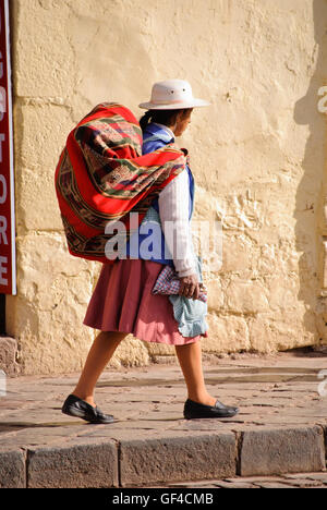 An Andean Indian woman in half traditional costume walking on a street in Cuzco Stock Photo