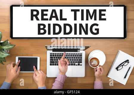 REAL TIME BIDDING Two Businessman working at office desk and using a digital touch screen tablet and use computer, top view Stock Photo