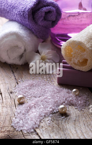 Spa.Lilac bath salt, sponge,lotion and towels on wooden background. Selective focus Stock Photo