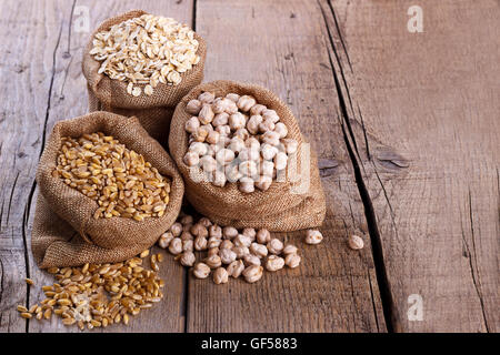 Cereals for a healthy diet, wheat,oatmeal and chickpeas in sacks on rustic wooden background Stock Photo