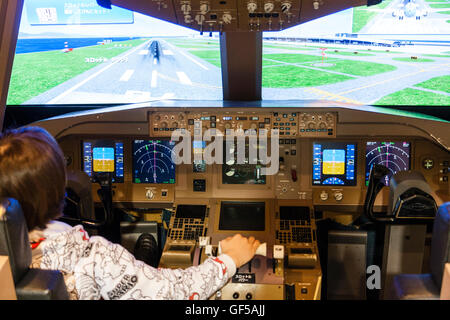 Japan, Osaka, Kansai airport, KIX. Sky Museum, interior. Caucasian child, 14 year old boy, sitting in cockpit of a flight simulator. Hands on controls. Stock Photo