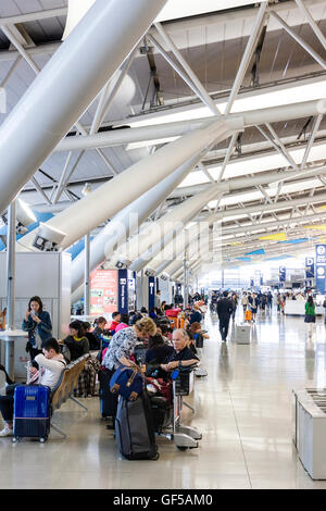 Japan, Osaka, Kansai airport, KIX. Interior of terminal. International check-in. View along of people sitting in seating area by roof supports. Stock Photo