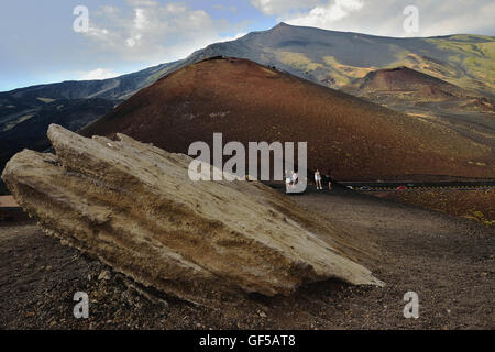 Tourists visiting the volcano Etna, Sicily, Italy. Scenic view of red ground by dry lava hills, stormy sky with space for text Stock Photo