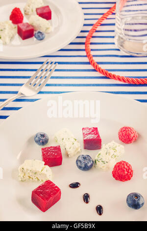 Retro toned appetizer made of beet, cottage cheese with fruits on sailing style decorated table. Stock Photo