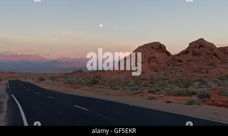 The moon rises over the deep oranges and cool blues of the Valley of Fire state park in Nevada, USA. Stock Photo