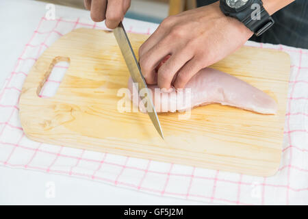 man in the kitchen cooking roast pork: cutting meat. Stock Photo