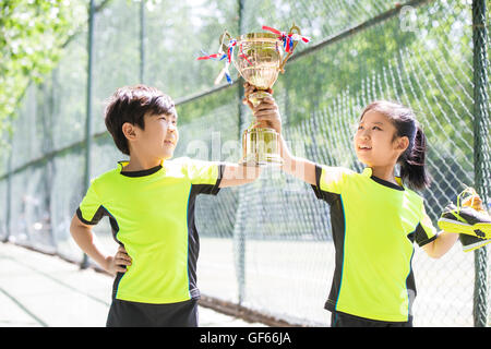 Happy Chinese children in sportswear showing their trophy Stock Photo