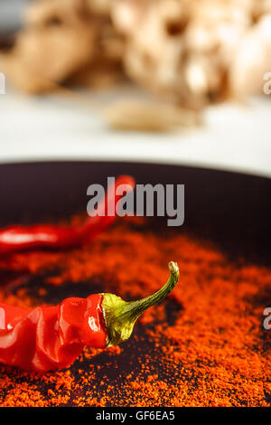 Closeup red pepper with ground paprika on brown dish over white wood. Vertical image. Stock Photo