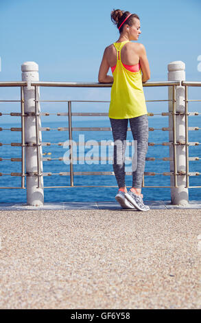 Look Good, Feel great! Seen from behind young healthy woman in fitness outfit looking aside at the embankment Stock Photo