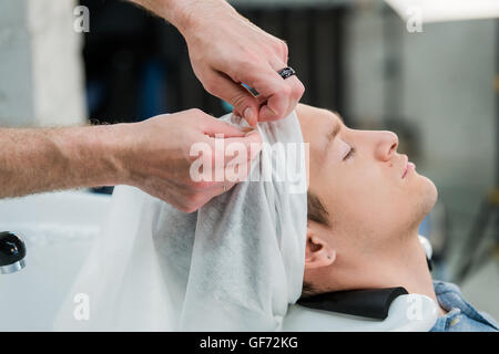 Hairstylist washing client's hair in barber shop Stock Photo