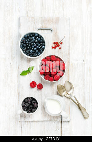 Fresh garden berries in bowls on white painted wooden background Stock Photo