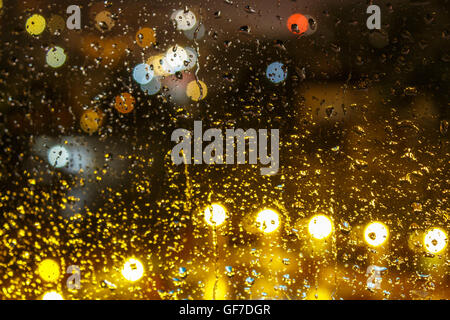 abstract background raindrops on glass on background of blurred warm  with cool blue and purple lights with bokeh effect Stock Photo