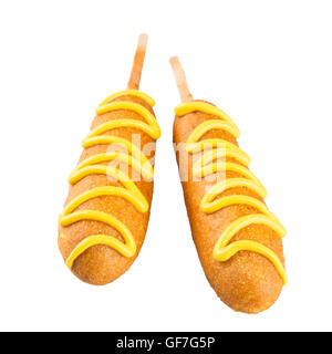 Two corn dogs isolated on a white background topped with mustard Stock Photo