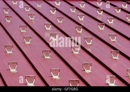 Clear plastic snow guards or snow stops attached to a sloping wooden roof Stock Photo