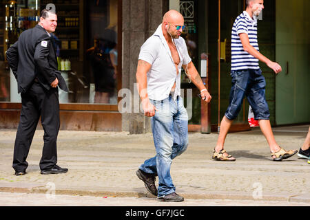 Goteborg, Sweden - July 25, 2016: Unknown male walking by on the sidewalk with a very hard and tense style while listening in ea