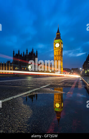 View of the Big Ben with reflexion on a pothole and with some light trails - London, UK Stock Photo