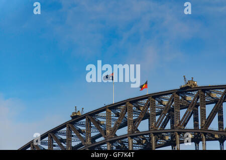 The Australian and Aboriginal flags stand proudly at the top of the arch of the Sydney Harbour Bridge in Australia Stock Photo