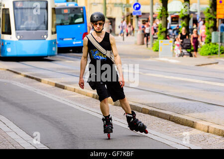 Goteborg, Sweden - July 25, 2016: Young adult man roller skating towards you with trams in the background. Real people in everyd