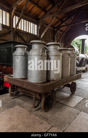 Milk churns on a rail truck in a train shed at the Didcot Railway Centre in Oxfordshire Stock Photo