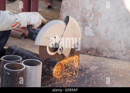 closeup on electric saw and hands of worker with sparks. Stock Photo
