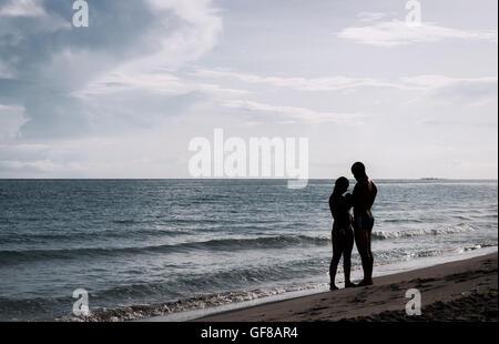silhouette of a couple on the beach with the sea and sky as background Stock Photo
