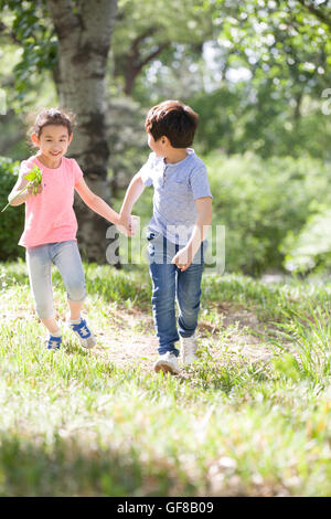 Happy Chinese children holding hands running in woods Stock Photo - Alamy