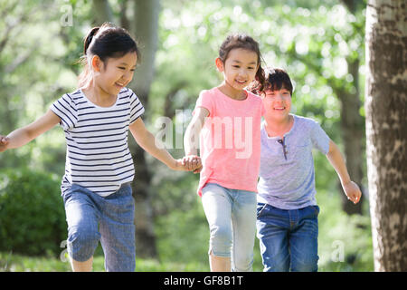 Happy Chinese children holding hands running in woods Stock Photo - Alamy