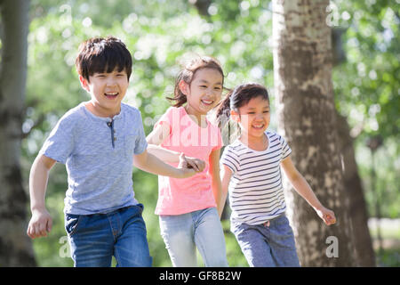 Happy Chinese children holding hands running in woods Stock Photo - Alamy