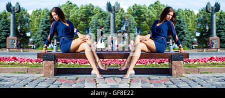Beautiful young woman sits on a bench in a summer park Stock Photo