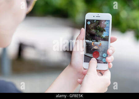 Varna, Bulgaria - Jul 20, 2016: A woman battles Krabby pokemon while playing the Nintendo augmented reality mobile game Pokemon Go on Apple iPhone 6S. Stock Photo