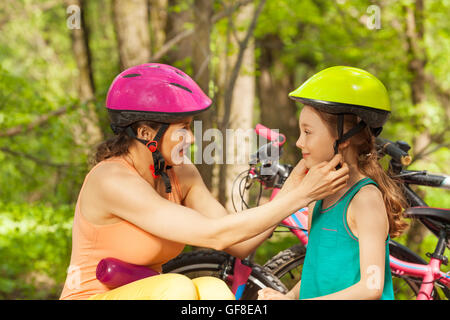 Sporty mother helping her daughter to clasp helmet Stock Photo