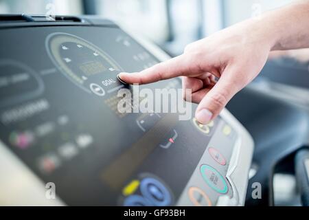 PROPERTY RELEASED. Man pushing control panel button of exercise machine, close-up. Stock Photo
