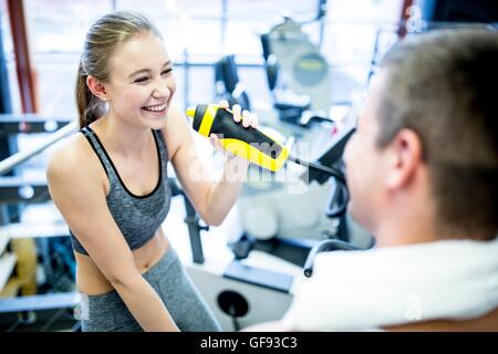 PROPERTY RELEASED. MODEL RELEASED. Young woman drinking water in gym, smiling. Stock Photo