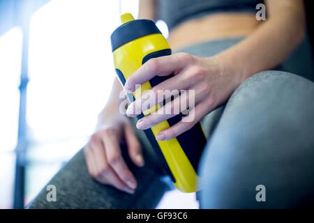 PROPERTY RELEASED. MODEL RELEASED. Woman holding water bottle in gym, close-up.
