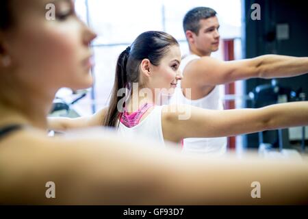 PROPERTY RELEASED. MODEL RELEASED. Young man and women doing warm up exercise in gym. Stock Photo